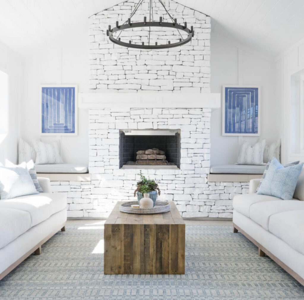 Stacked stone fireplace painted white in a modern beach house